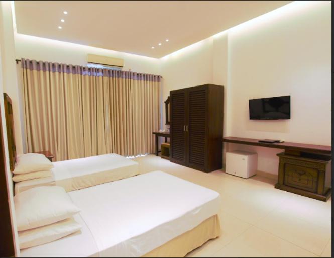 a hotel room with two beds and a television at Avasta Resort Wijaya Leisure in Anuradhapura