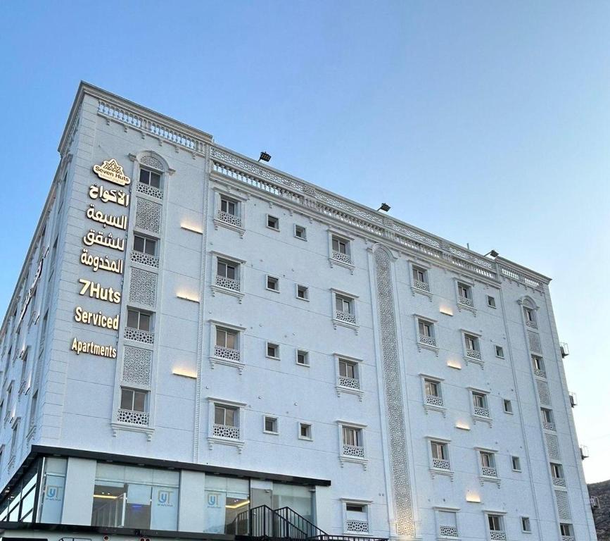 ターイフにあるشقق الاكواخ السبعة للشقق المخدومةの看板の付いた大きな白い建物