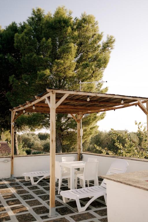 drewniana pergola z białymi krzesłami i stołem w obiekcie Casette Masseria La Camardia w mieście Sava