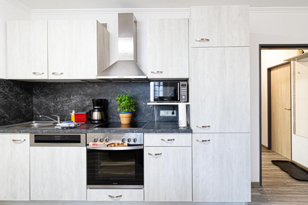 a kitchen with white cabinets and a stove top oven at Ferienwohnung Activities & Relax, Skilift&Downhill in Winterberg