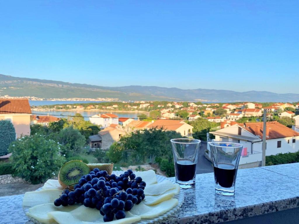 stół z talerzem owoców i dwa kieliszki w obiekcie Apartment Rozi w mieście Šilo