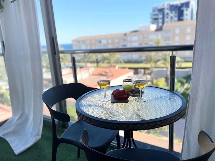 a table with two glasses of wine on a balcony at La dama del mar in Punta Prima