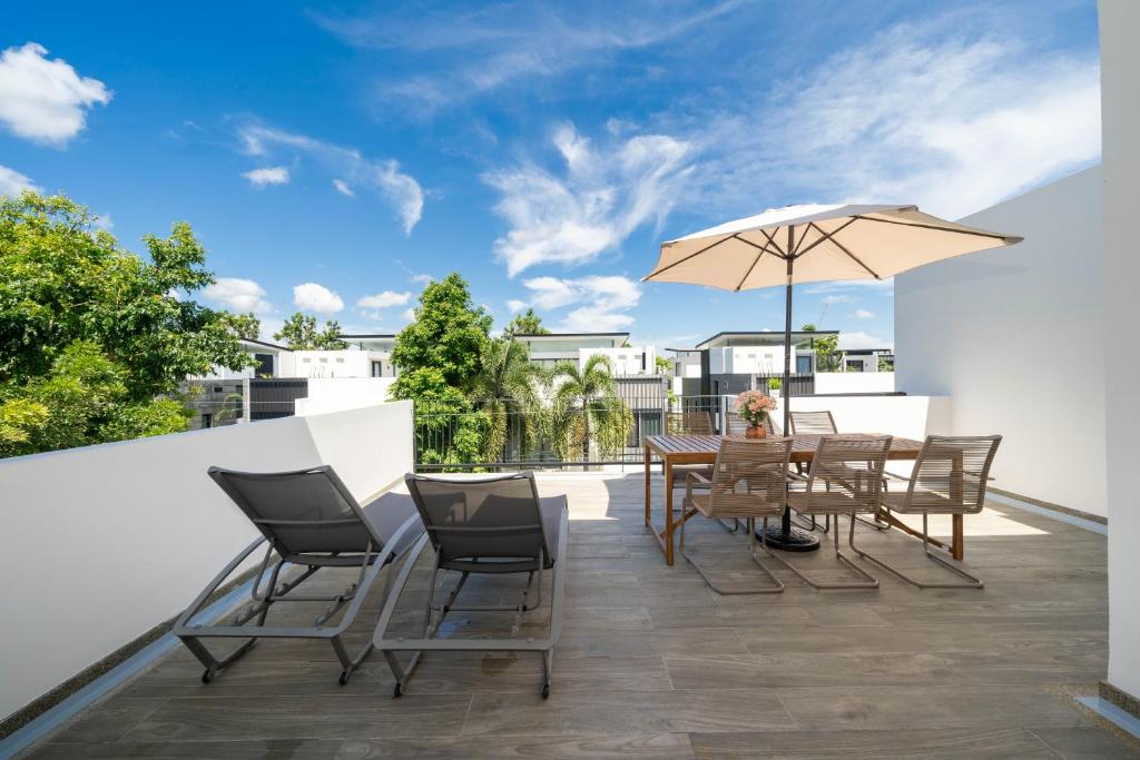 a patio with a table and chairs and an umbrella at Laguna pool house in Phuket Town