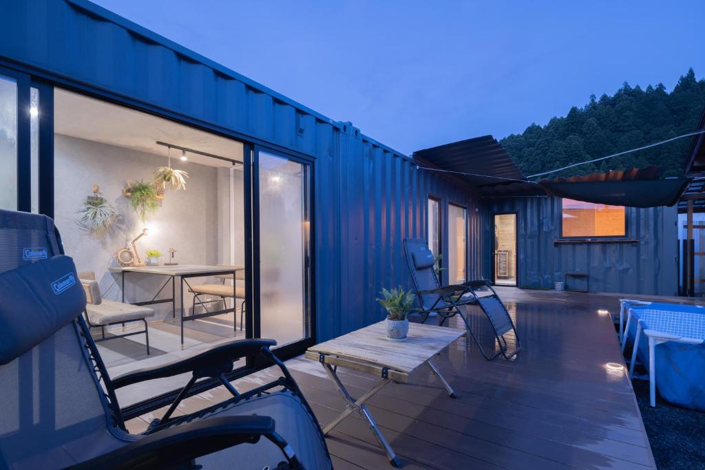 a blue house with a deck with a table and chairs at Riverside Sauna Base Conpeki in Taniai