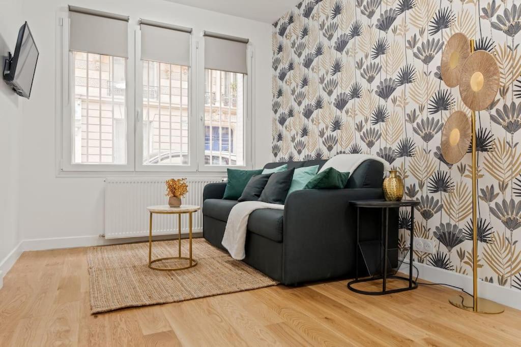 - un salon avec un canapé noir et un mur dans l'établissement Perfect Emplacement Paris - Metro 1 min - Tour Eiffel 10min - Netflix, à Paris