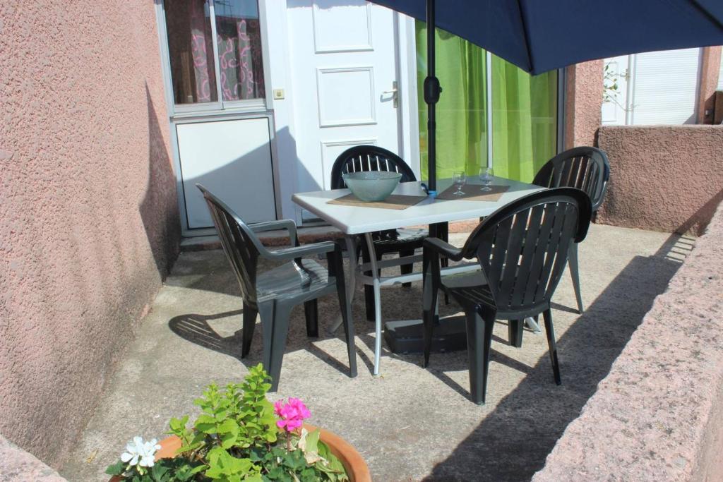 une table et des chaises avec un parasol sur une terrasse dans l'établissement Beau T3 avec piscine collective proche Port,plage et commerces-4JDN822, à Saint Cyprien Plage