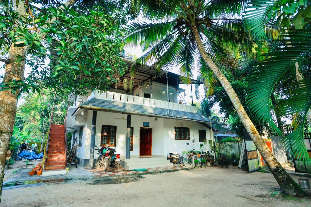 a white building with palm trees in front of it at Marari Moriyah Homestay in Mararikulam