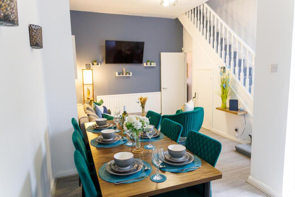 ein Esszimmer mit einem Holztisch und grünen Stühlen in der Unterkunft Stylish 6-Bedroom House, Ideal for Contractors! in Monkwearmouth