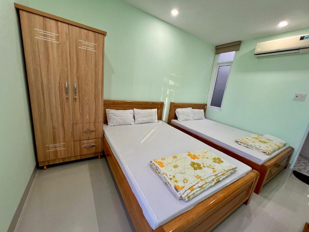 a bedroom with two beds and a wooden cabinet at HT Phuong Thao Boutique in Nha Trang