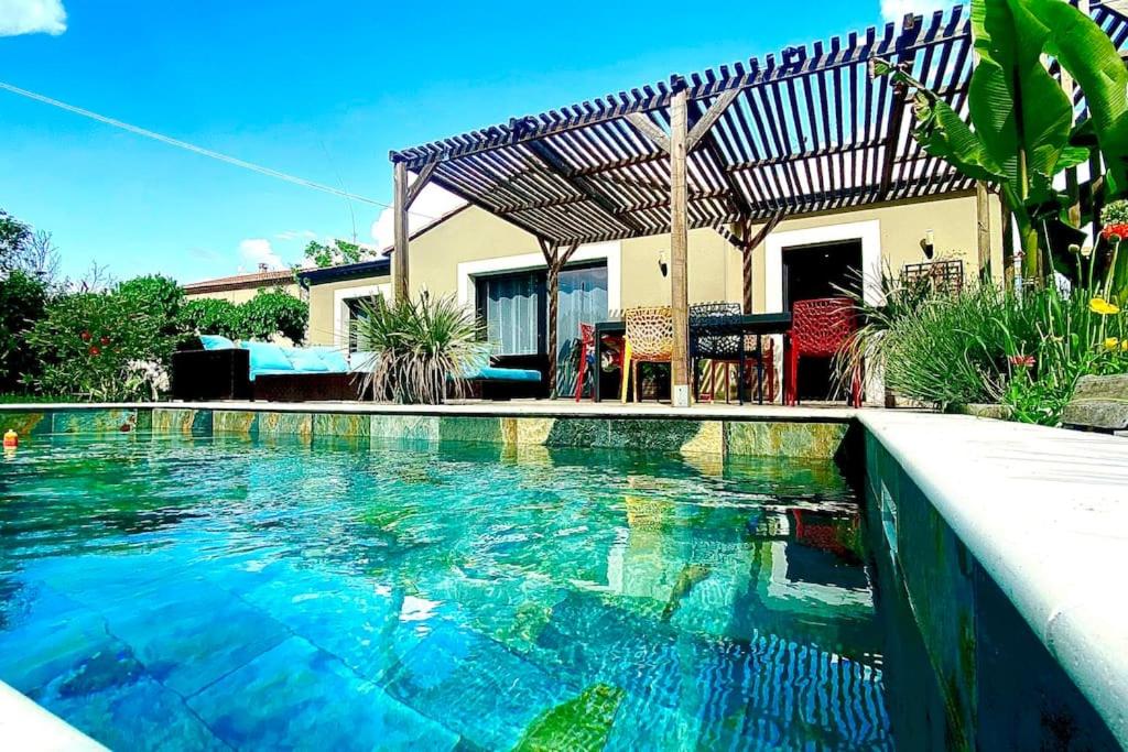 une piscine avec de l'eau bleue devant une maison dans l'établissement Villa avec piscine entre terre et mer, à Saint-Hilaire-de-Brethmas
