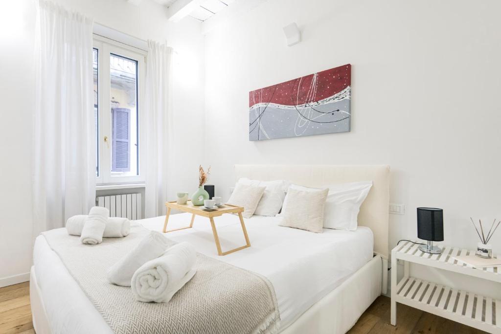 biała sypialnia z 2 łóżkami i stołem w obiekcie Amazing, new & fully furnished studio in Duomo w Mediolanie