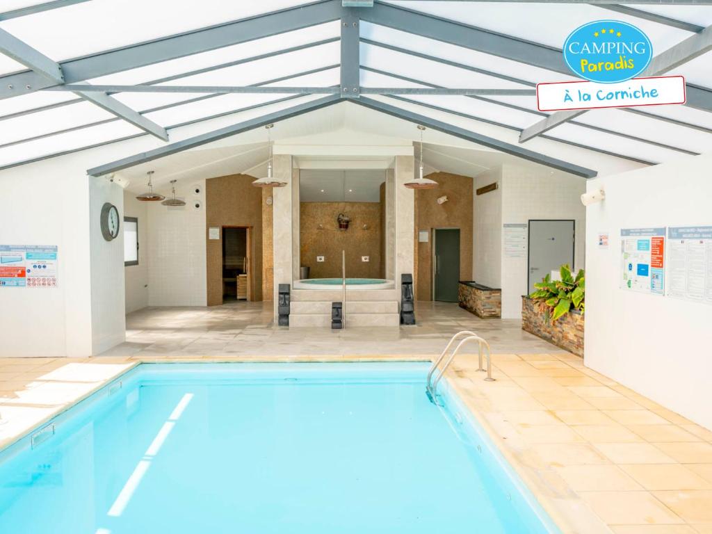 a swimming pool in a building next to a house at Camping Paradis 4 étoiles A La Corniche La Rochelle Angoulins in Angoulins-sur-Mer