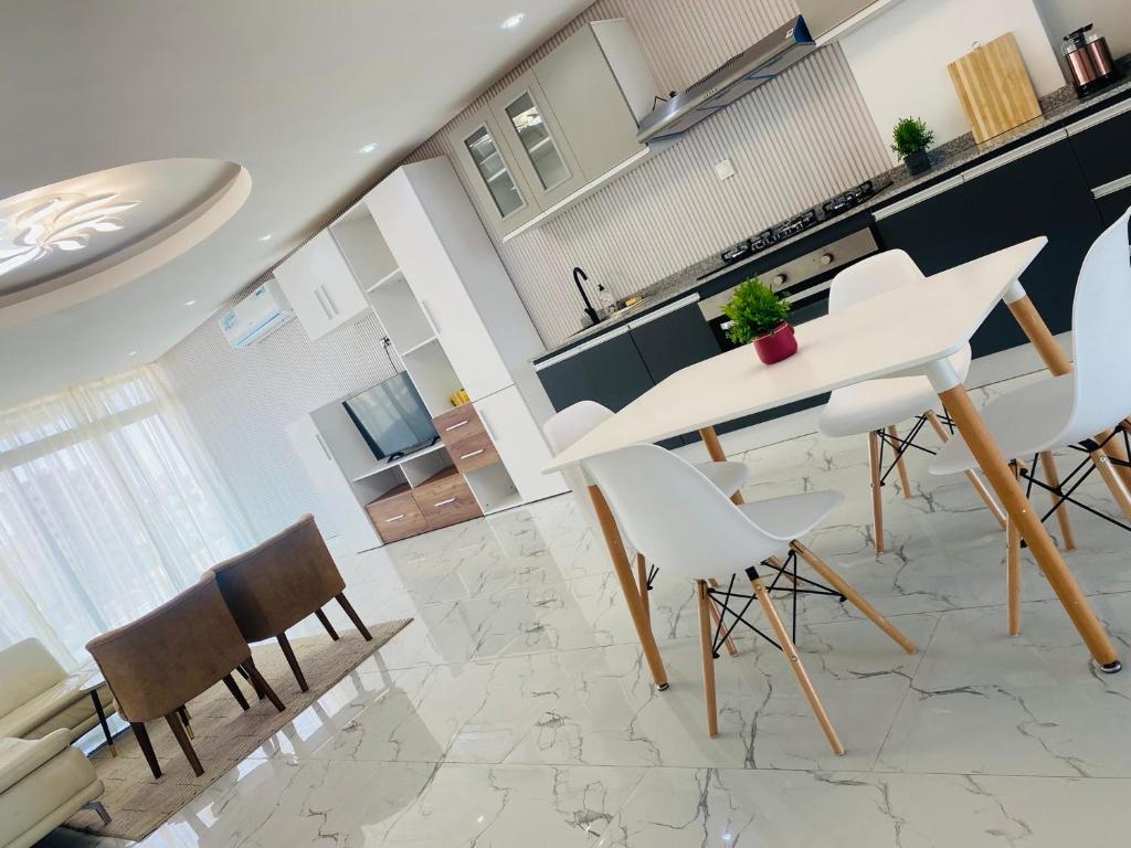 CHEZ EL HADJI NGOR في داكار: مطبخ وغرفة طعام مع طاولة وكراسي بيضاء