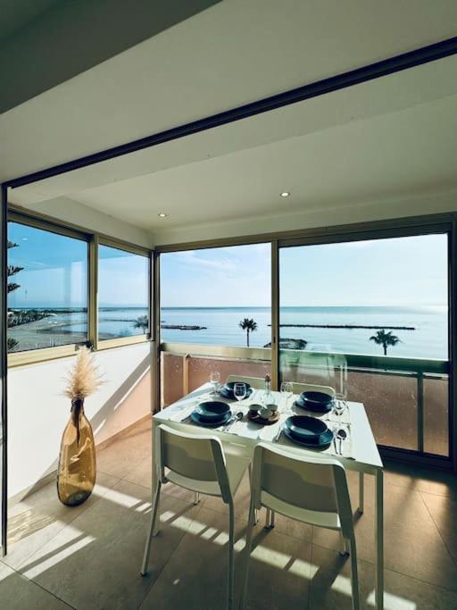 une table et des chaises dans une pièce avec vue sur l'océan dans l'établissement Évasion Mer & Vue Imprenable, à Saint-Laurent-du-Var