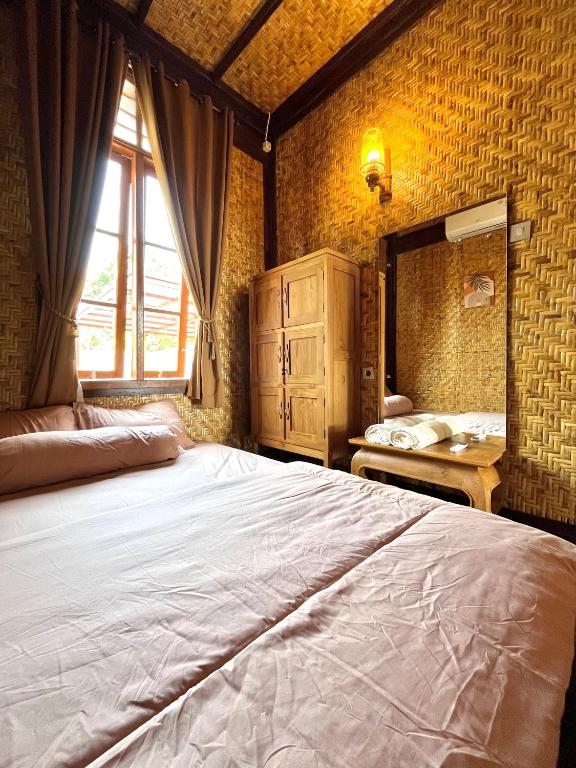 a bedroom with a large bed and a window at Joglo Homestay Banyuwangi in Banyuwangi