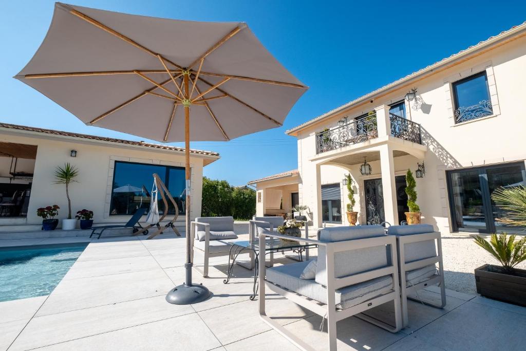 un patio avec une table, des chaises et un parasol dans l'établissement Appartement de vacances Carsac 1, à Carsac-de-Gurson