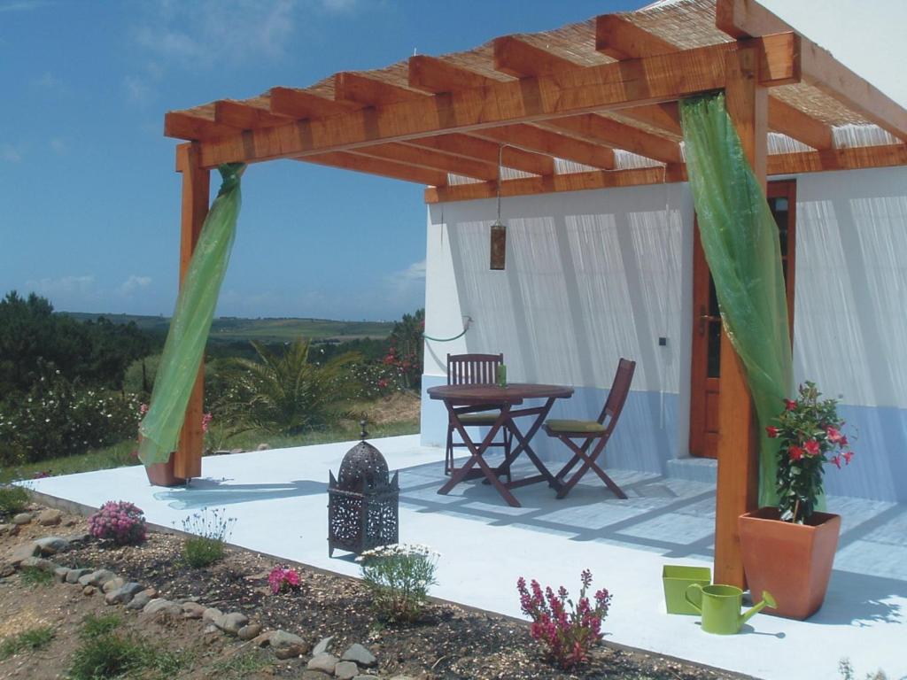 a patio with a wooden pergola and a table at Monte da Xara in Aljezur