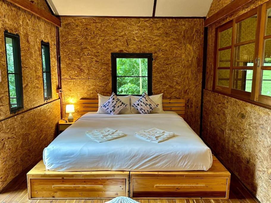 una camera da letto con un letto con due asciugamani sopra di Bangtao Wooden house resort and cafe a Ban Thalat Choeng Thale
