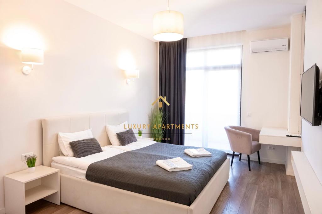 a white bedroom with a bed and a desk at Luxury Apartments “Dream City” in Uzhhorod