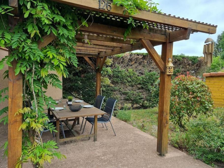 une table et des chaises en bois sous une pergola en bois dans l'établissement La maison des glycines, à Onesse-et-Laharie