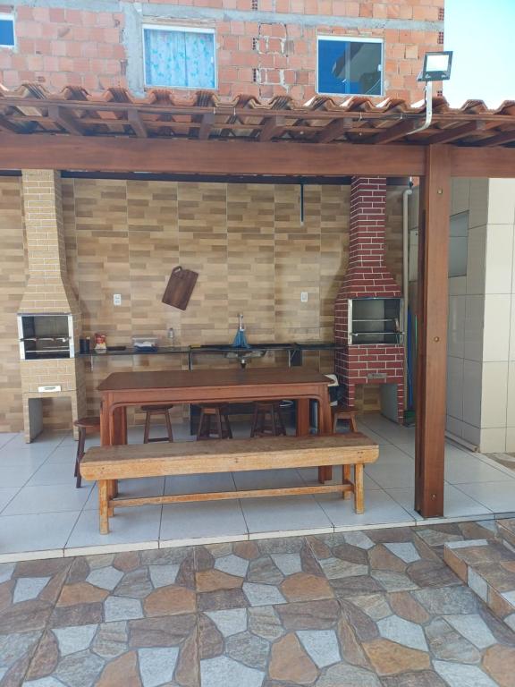 eine Terrasse mit einem Holztisch und Bänken in der Unterkunft Recanto do Mar em Peroba 02 in Maragogi
