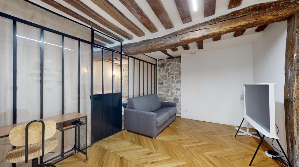 un salon avec une chaise et une télévision dans l'établissement 323 Suite Louis - Superbe Appartement à Paris, à Paris