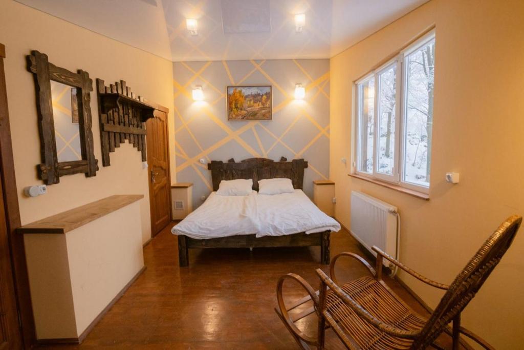 a bedroom with a bed and a chair in it at Готель Красія Резорт in Vyshka