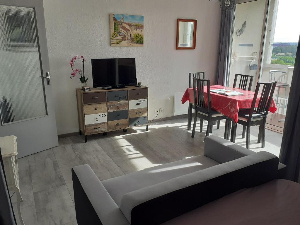 un soggiorno con tavolo, divano e TV di Studio greoux les bains a Gréoux-les-Bains