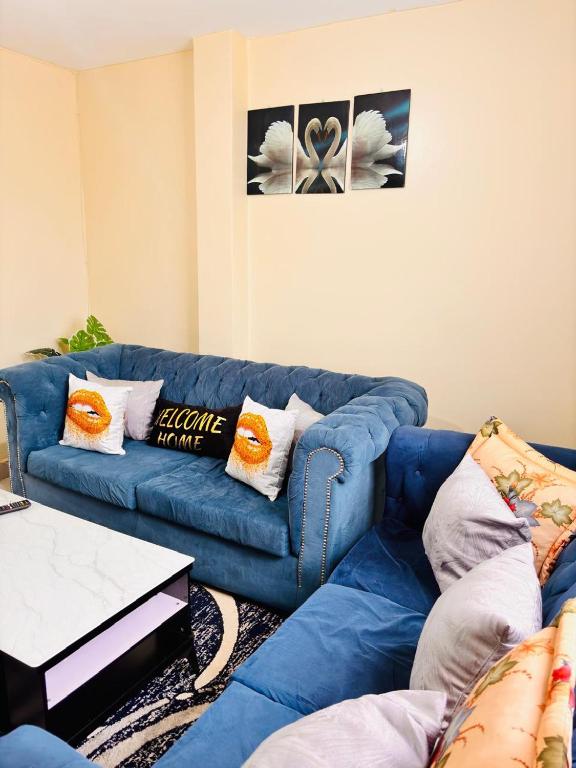 a living room with a blue couch with pillows at Olive Homes Thika Town in Thika