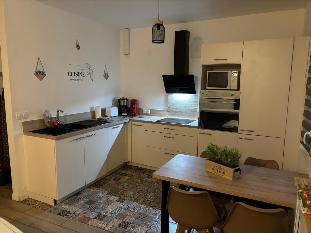 une cuisine avec des armoires blanches et une table en bois dans l'établissement el apartamento de julia, à Carcassonne