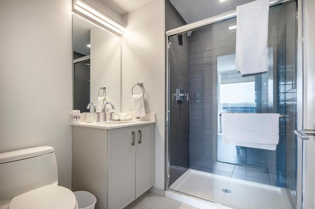 a white bathroom with a shower and a toilet at Luxury Apt with Gym & Pool in Stamford