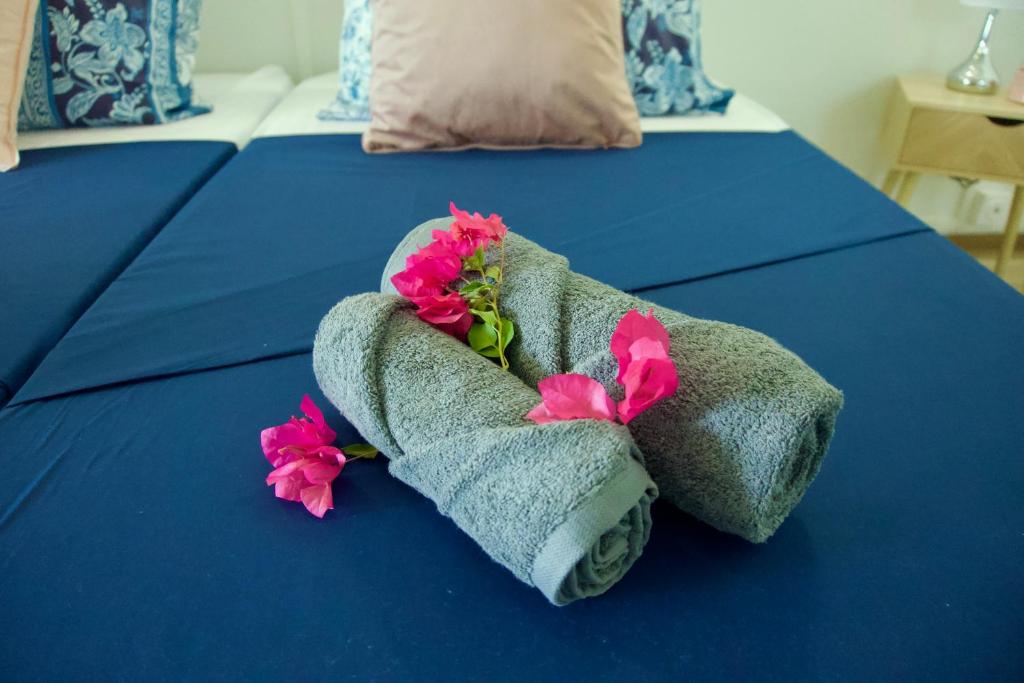 un letto blu con asciugamani e fiori di La villa Azur classée 3 étoiles Moderne et Confortable à deux pas de la plage de l Anse à l Ane Trois Îlets - Service Petit Dej sur demande a Les Trois-Îlets
