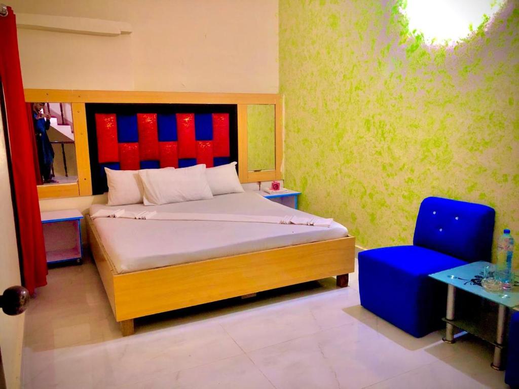 a bedroom with a bed and a blue chair at Malinum Grande Guest House in Lahore