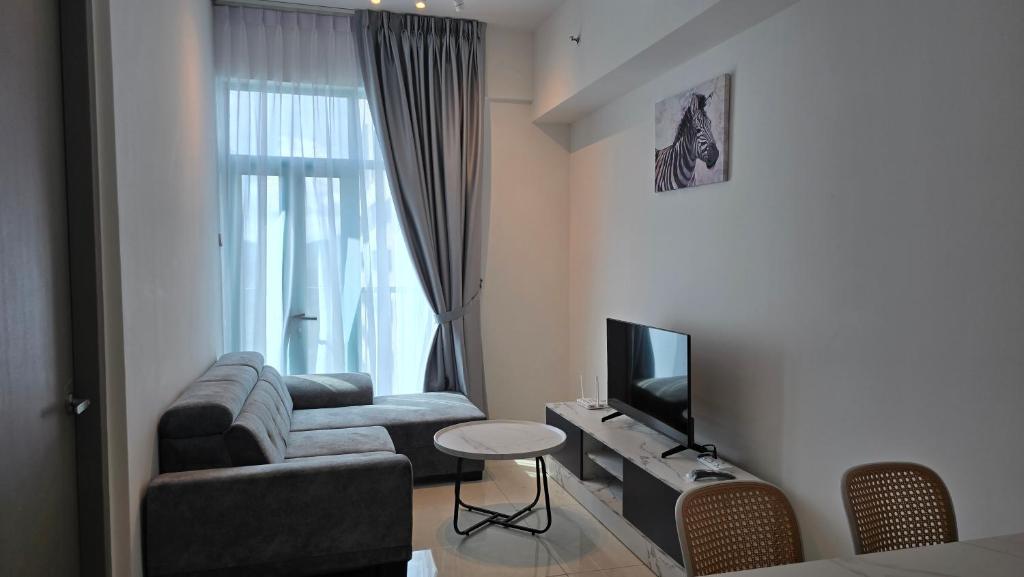 a living room with a couch and a television at BaySuites Likas by Alawa Homes in Kota Kinabalu
