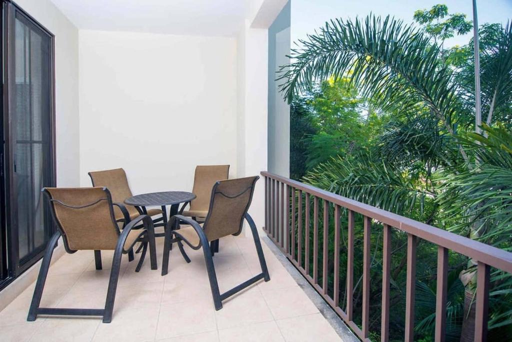 a balcony with a table and chairs and a palm tree at Spacious Beach-Inspired Condo with Resort-Style Amenities & Beach Club Access in Coco