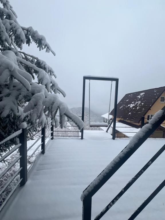 a boardwalk covered in snow next to a house at Cabana Zabet in Ranca