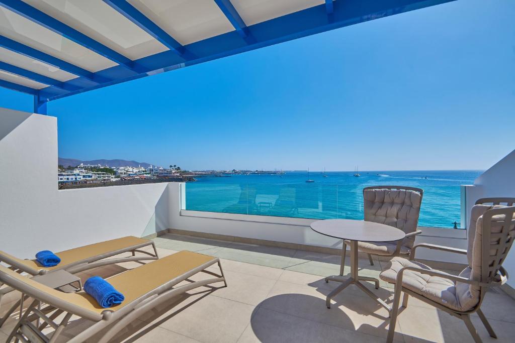 a balcony with chairs and a table and a view of the ocean at Blancazul Deluxe Casa Domingo in Playa Blanca