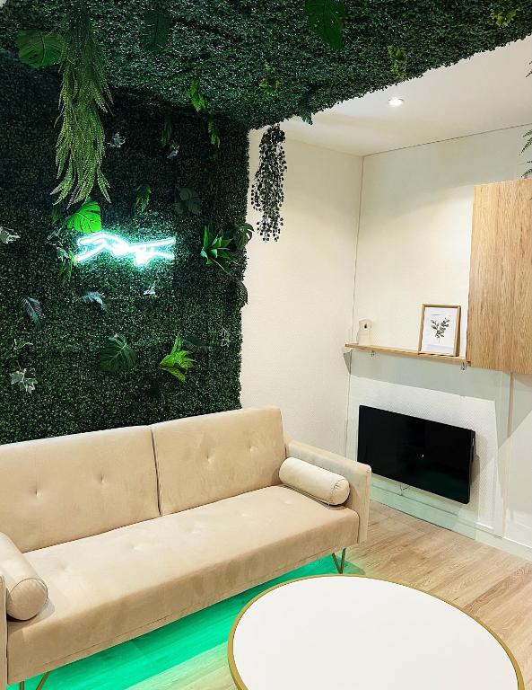 - un salon avec un canapé et un mur orné de plantes dans l'établissement Cosy Angevin - Joli petit appartement, à Angers