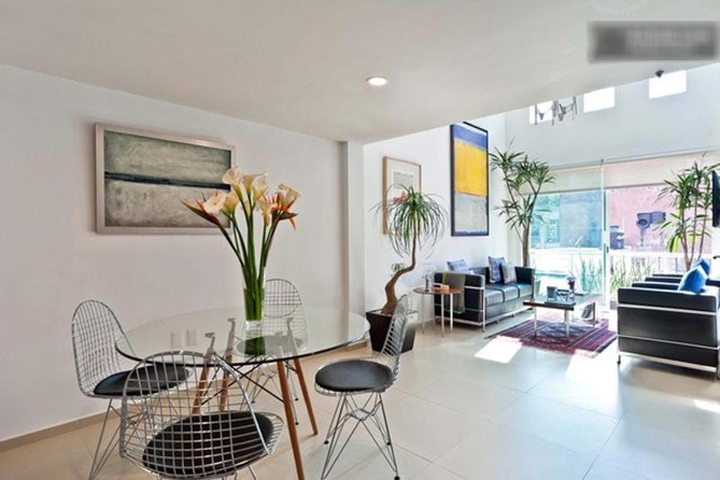 a living room with a glass table and chairs at Duplex Penthouse Zona Rosa in Mexico City