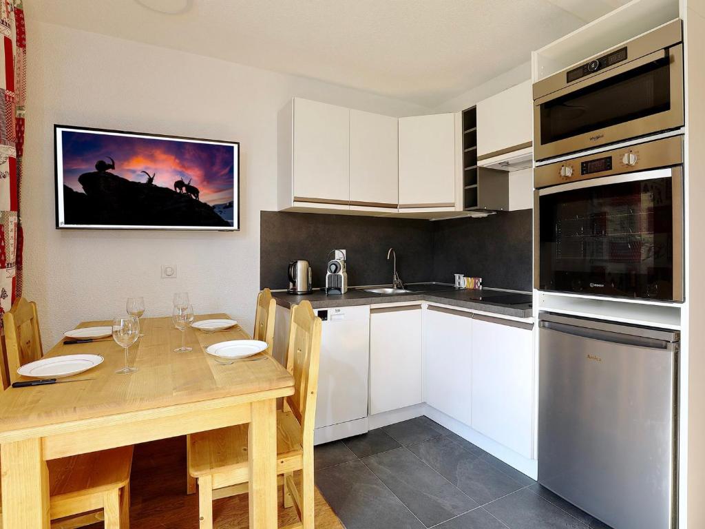 a kitchen with white cabinets and a wooden table at Appartement rénové proche des pistes - 4 pers, balcon, casier à skis - FR-1-575-211 in Courchevel
