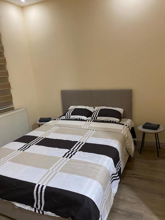 a bedroom with a large bed with black and white sheets at Stan na dan Nena 4 - Apartman Nena Užice in Užice