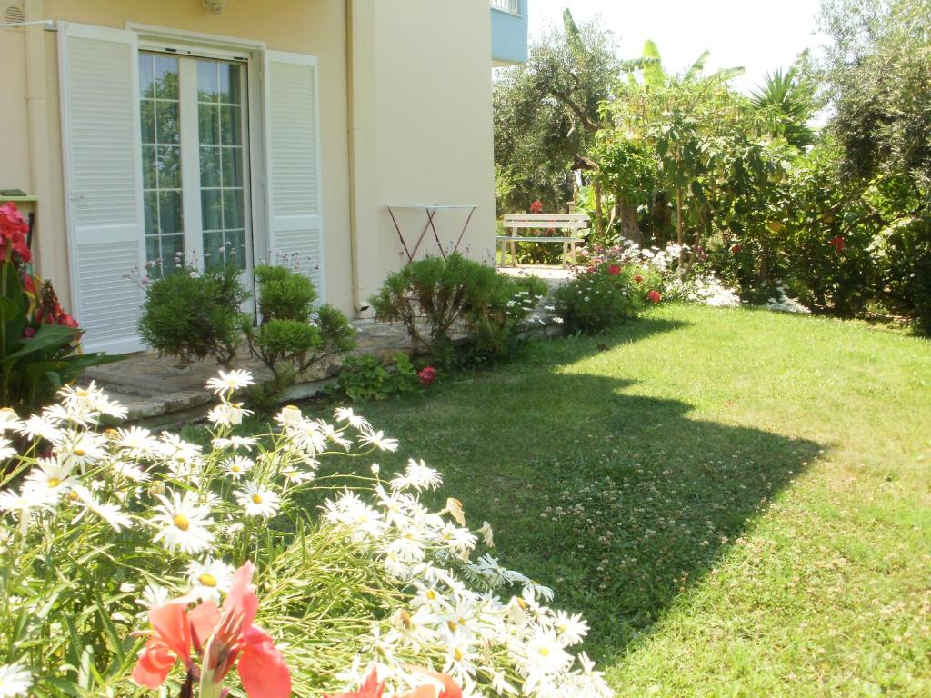 a yard with flowers and a house at Triantis Apartments in Ligia