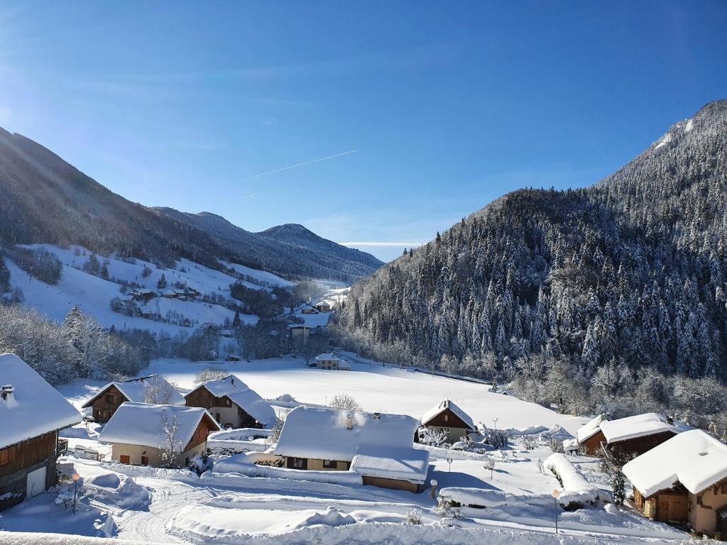 un pueblo cubierto de nieve con montañas en el fondo en L'Edelweiss, en Aillon-le-Jeune