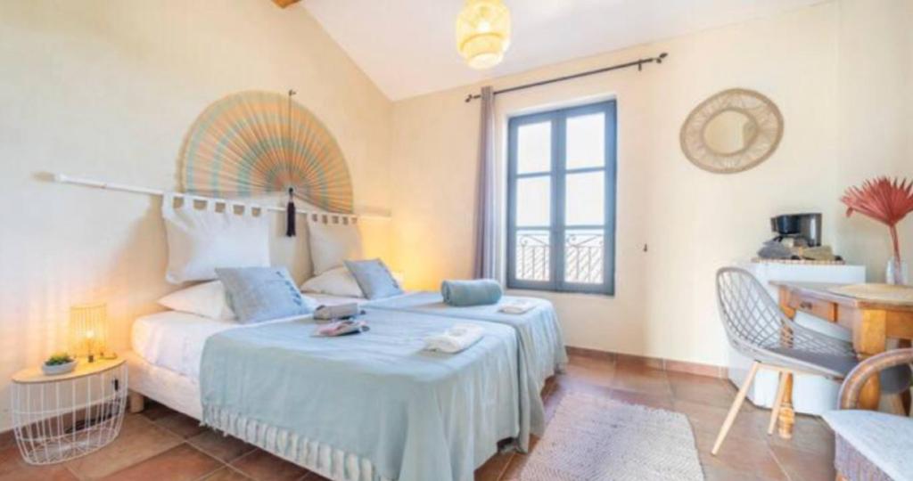 a bedroom with a bed and a table and a window at Maison Cosy Lodge 15 p clim wifi cour garage in Montfrin