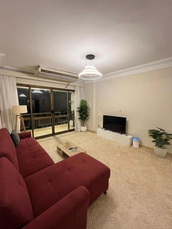 un soggiorno con divano rosso e TV a schermo piatto di Zamalek Taha Hussein open view a Il Cairo