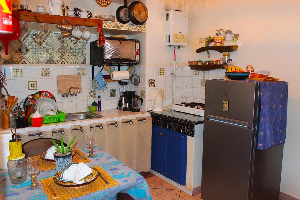 a kitchen with a refrigerator and a table in it at Asunfou : Appartement d'apaisement in Mirleft