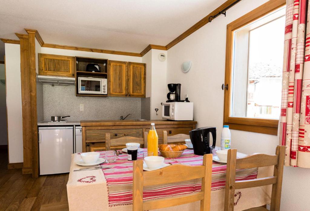 - une cuisine avec une table, une table et des chaises dans l'établissement Résidence Le Clos Vanoise - Appartement 3 pièces lumineux MAE-4551, à Bessans