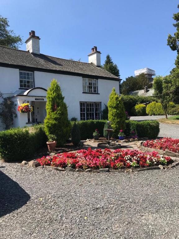 a house with a bunch of flowers in the driveway at Old School House - with private onsite parking in Hawkshead