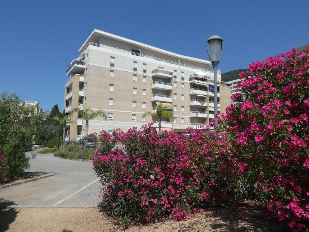un grand bâtiment avec des fleurs roses devant lui dans l'établissement Ajaccio Sanguinaires T2 150métres de la mer, à Ajaccio