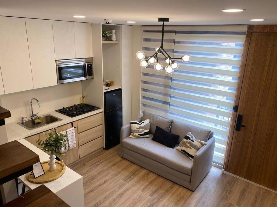 a living room with a couch and a kitchen at Apartamento con encanto cerca del centro de Cuenca in Cuenca